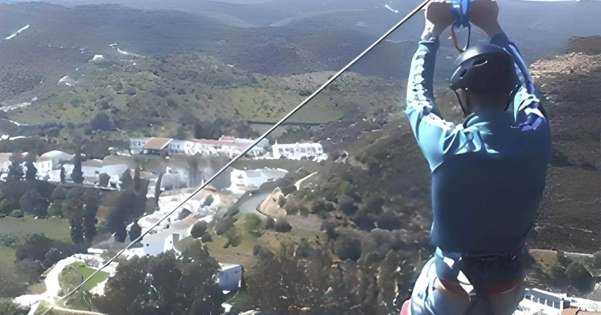 Pessoa fazendo tirolesa sobre paisagem natural.